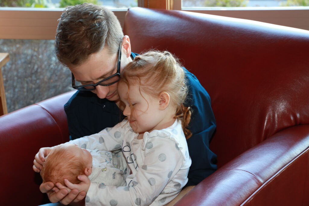 Father and young daughter holding a baby